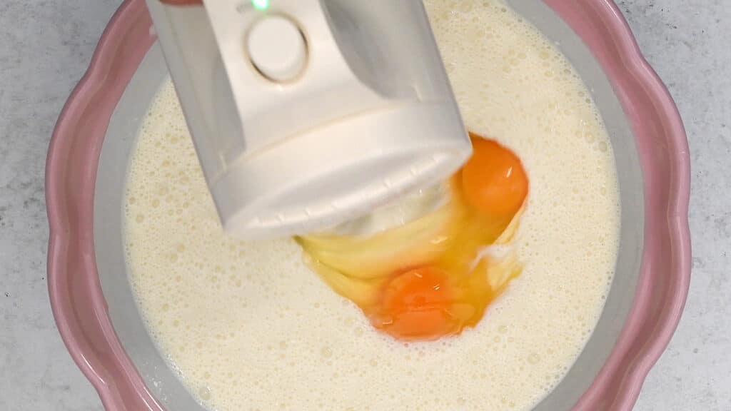 beating the filling for cheesecake with an electric hand mixer