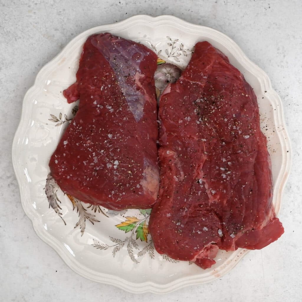braising steaks on a plate seasoned with salt and pepper