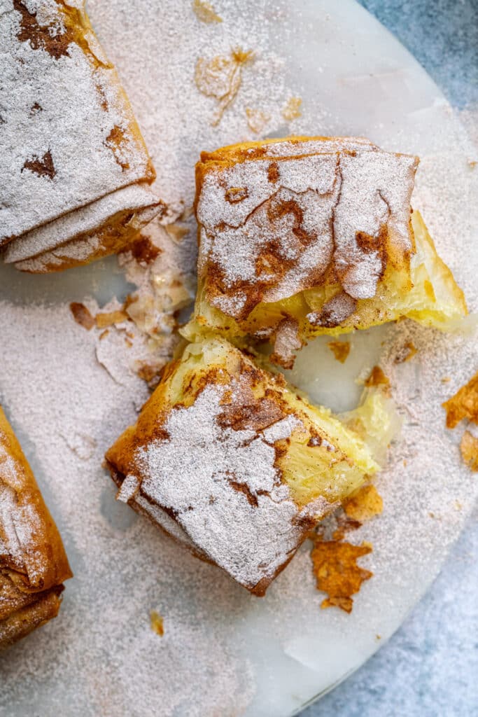 Close up on Greek Bougatsa sliced in half to show the creamy custard filling and crisp filo pastry