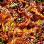 close up on Chinese crispy chilli beef garnished with sesame seeds and spring onions