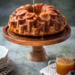 Bacardi rum cake on a cake stand being drizzled with rum glaze