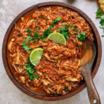 bowl of Mexican Chicken Tinga garnished with cilantro and lime wedges