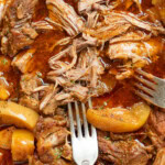 Close up on cider braised pork shoulder, two forks shredding the meat.