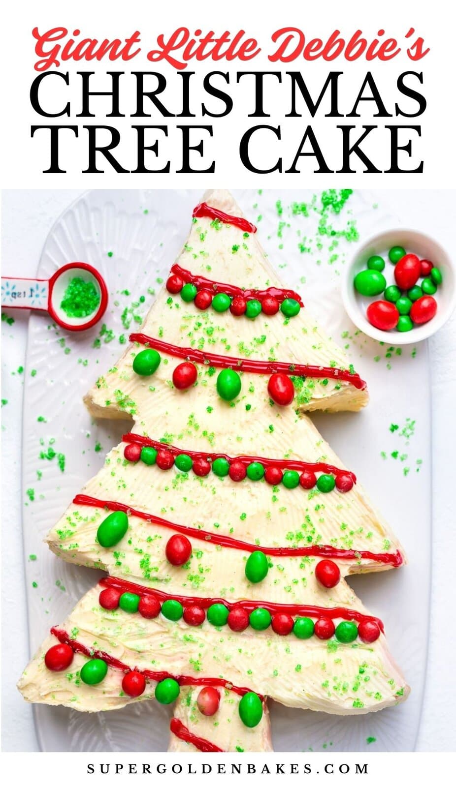 A large, homemade Christmas Tree Cake decorated with white frosting, red and green candies, and green sprinkles sits on a white tray with a spoon and bowl of sprinkles. Text above reads Giant Little Debbies Christmas Tree Cake.