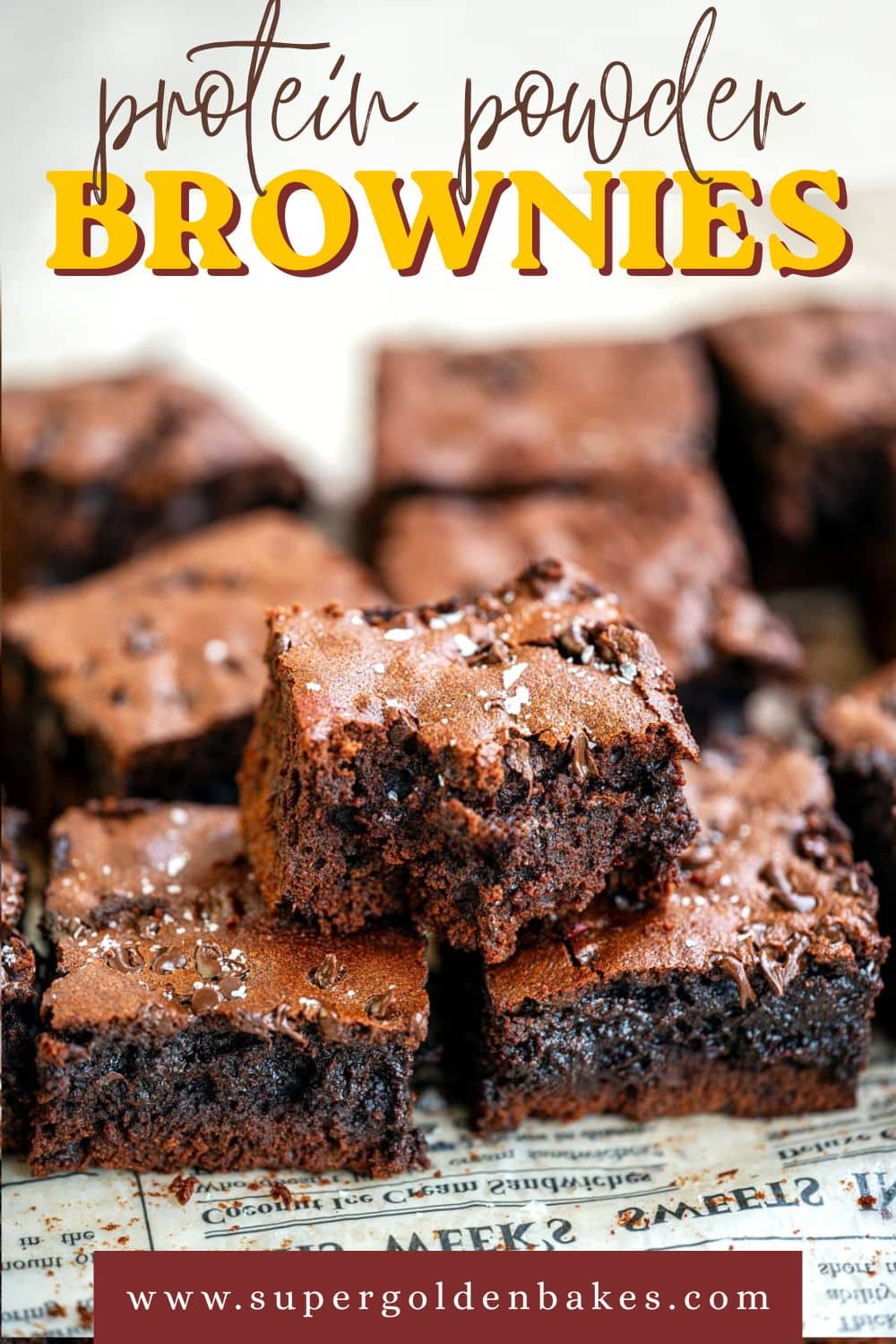 Close-up of rich protein brownies sprinkled with sea salt, arranged in a group. Text on image reads “protein powder brownies” and “www.supergoldenbakes.com” at the bottom.