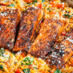 A one pan skillet filled with four Cajun Salmon Orzo fillets atop creamy orzo pasta with spinach and tomatoes, all topped with grated cheese.