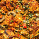Golden-brown chicken thighs cooked in a creamy chicken paprika sauce with mushrooms, spinach, red bell peppers, and herbs, topped with grated cheese and fresh thyme. This rich, colorful dish bursts with flavor in every bite.