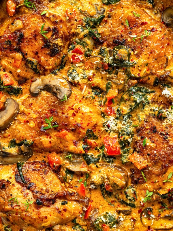 Golden-brown chicken thighs cooked in a creamy chicken paprika sauce with mushrooms, spinach, red bell peppers, and herbs, topped with grated cheese and fresh thyme. This rich, colorful dish bursts with flavor in every bite.