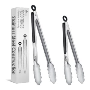 Two stainless steel kitchen tongs are shown next to their packaging box, which features images and descriptions of the tongs. The tongs have scalloped edges and black grip handles.
