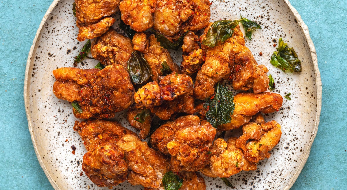 A plate of golden Taiwanese fried chicken, or yan su ji, scattered with crisp fried basil leaves