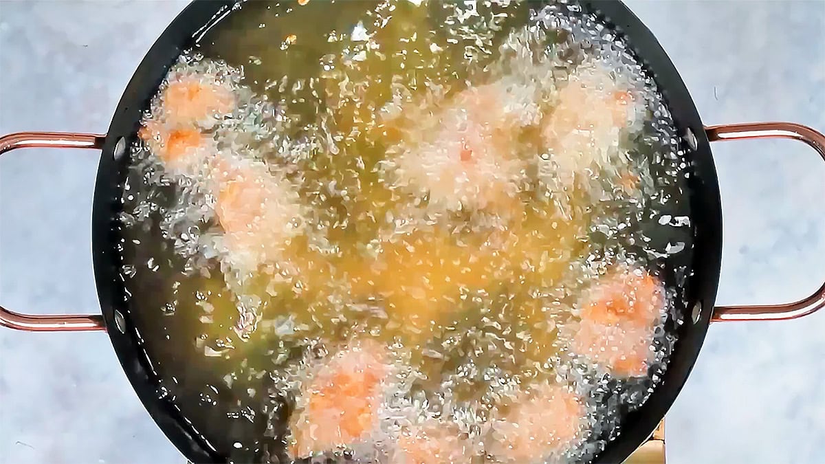 Taiwanese fried chicken frying in hot oil in a black pan, seen from above