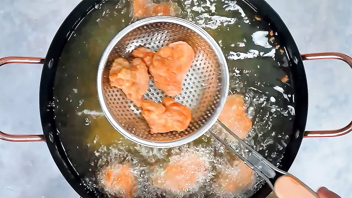 Lifting crispy Taiwanese fried chicken out of the hot oil with a spider strainer