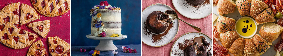Four desserts: heart-cut pie slices, flower-topped white cake, two plates of chocolate lava cake with spoons, and a round bread wreath with dipping sauce, meats, and olives on a pink tablecloth.