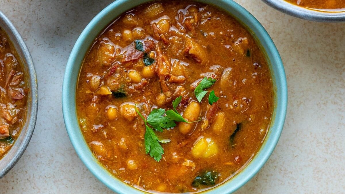 Three bowls of thick ham and bean soup garnished with fresh parsley.