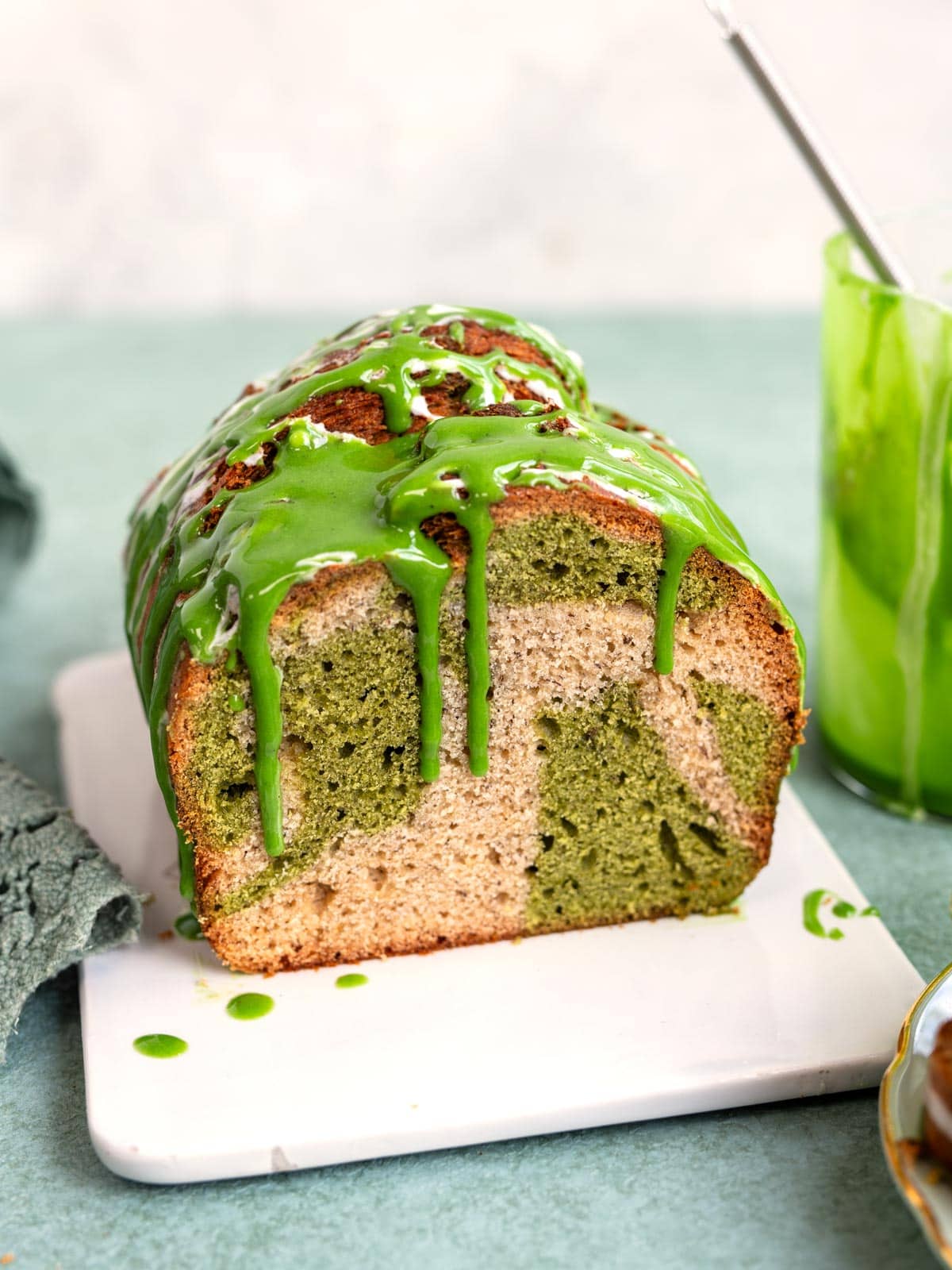 A slice of marbled matcha banana bread drizzled with green matcha icing.