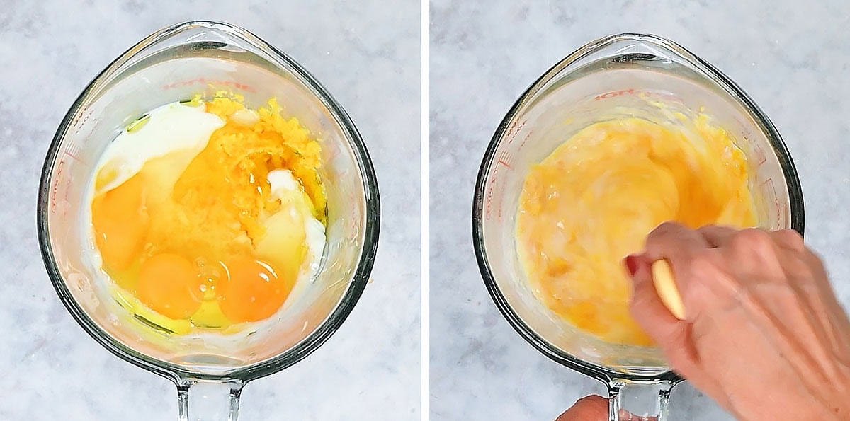A glass measuring cup holds raw eggs, milk, and grated cheese for a chocolate orange cake recipe, with a small bowl of white powder nearby.