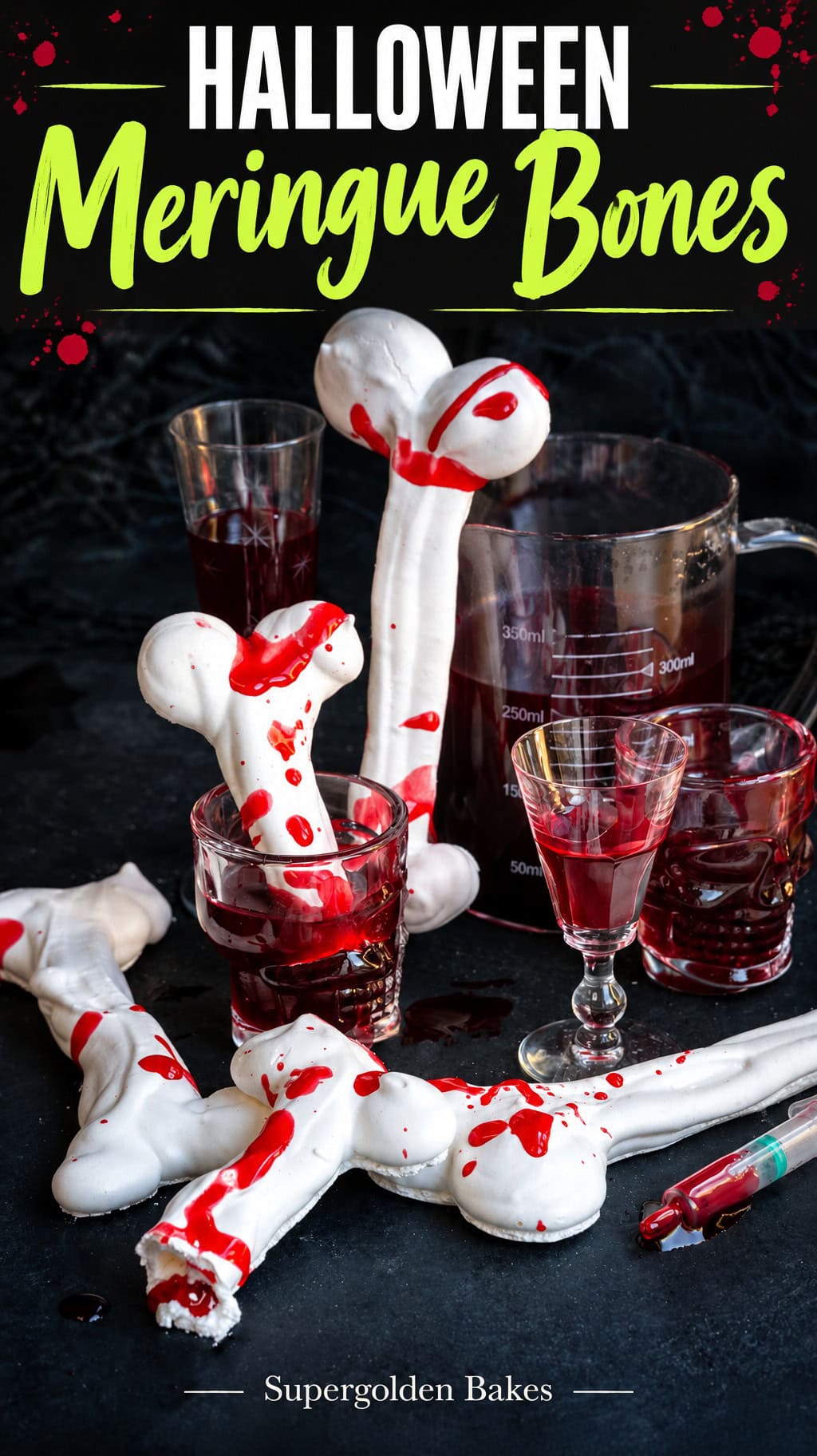 White meringue bones decorated with red food coloring to resemble blood, placed among glasses of red liquid and a syringe on a black surface, captioned Halloween meringue bones.